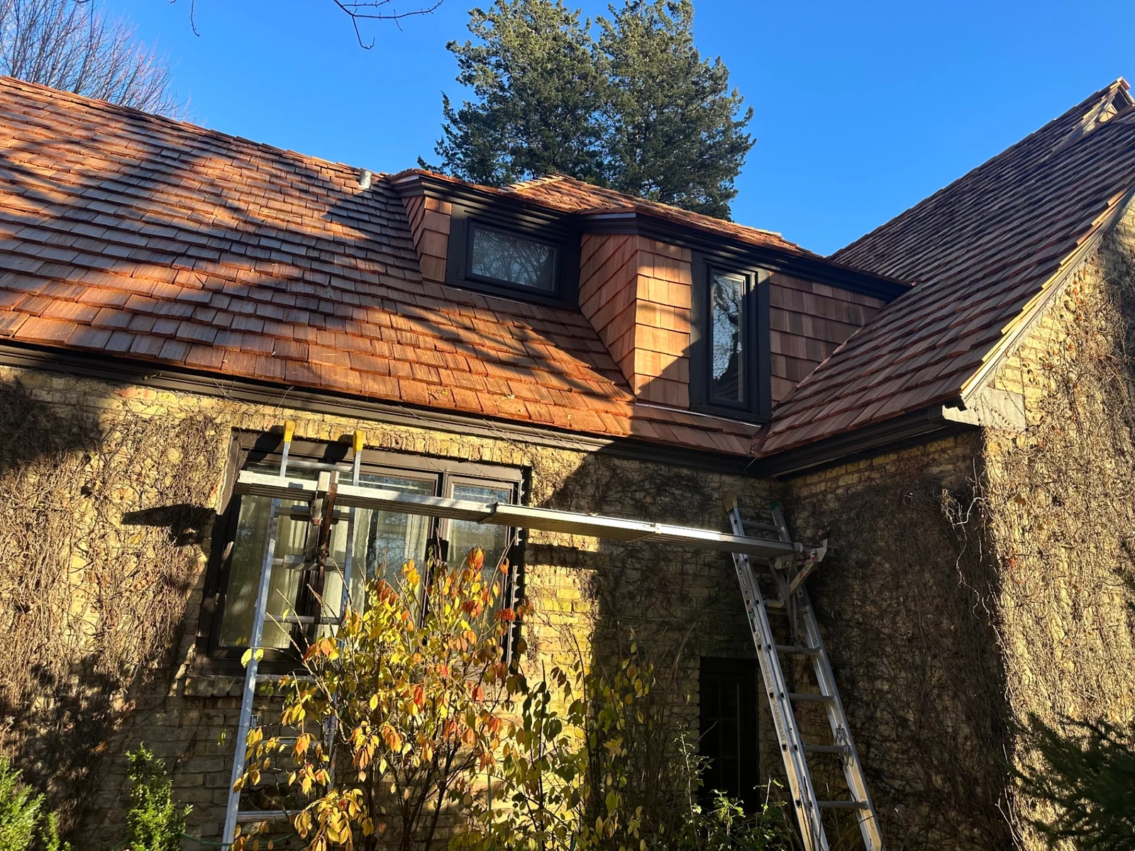Completed cedar shake dormer roof with custom copper-tone trim by Avilas Construction